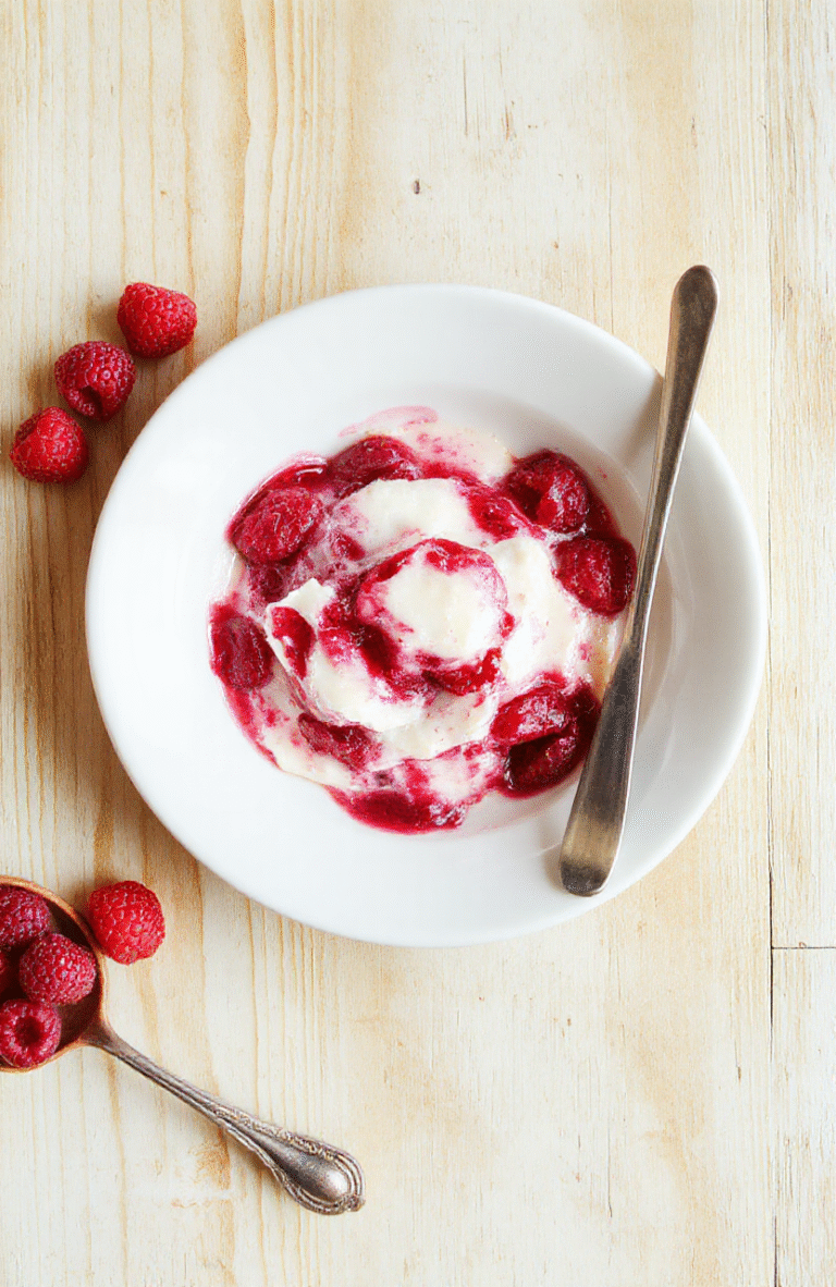 Ein goldbrauner Gugelhupf mit marmoriertem Muster, bestäubt mit Puderzucker, serviert auf hellem Teller, garniert mit frischen Himbeeren.