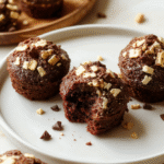 Mini Maulwurfkuchen-Törtchen mit dunklem Keksboden, cremiger heller Füllung und Kakao-Topping, serviert auf hellem Holztisch; ansprechende, glatte Textur und feine Krümel.